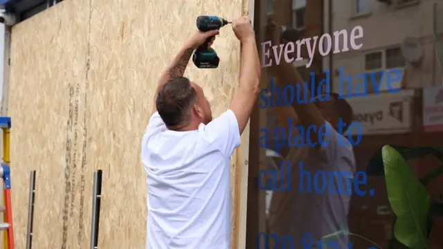 A person boards up windows as a protective measure against damage from riots, in preparation for more unrest amidst anti-immigration related rioting across the country, in London, Britain, August 7, 2024