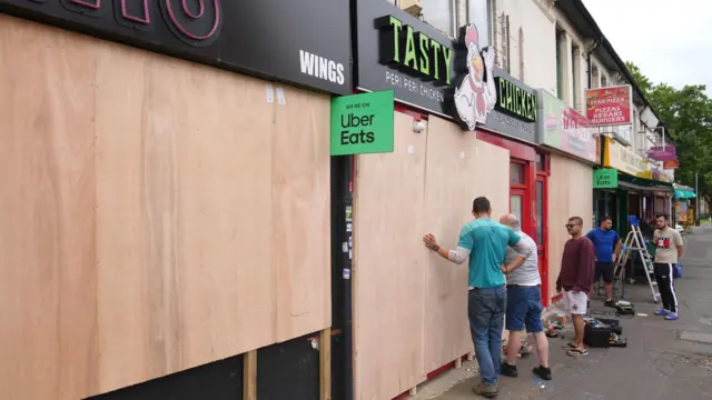 People boarding up windows and shop fronts