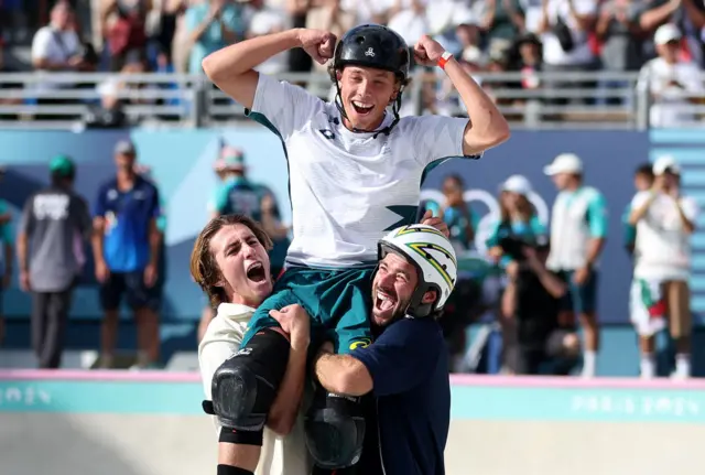 Carew and Barros lift Palmer into the air after his gold medal ride