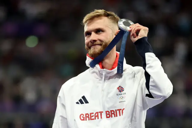 Great Britain's Josh Kerr holding his silver medal up to the crowd