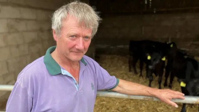 Farmer Andrew Bebb standing next to an enclosure wearing a purple shirt