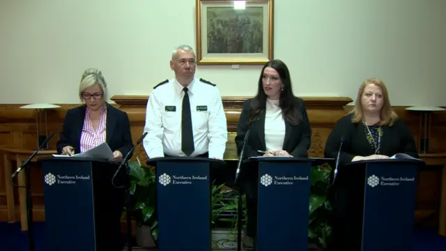 Michelle O'Neill, Jon Boutcher, Emma Little Pengelly and Naomi Long stahbd at the podium
