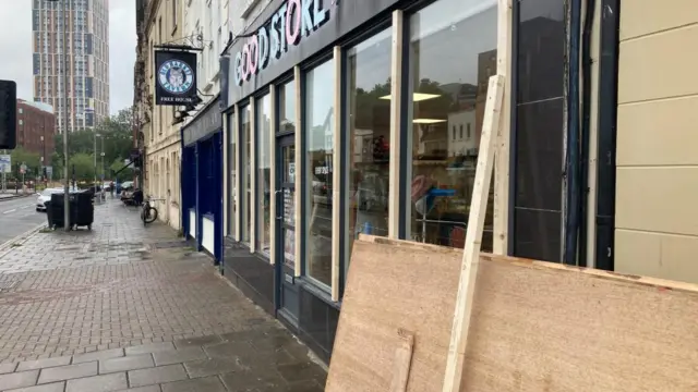 A picture of a shop with boarding beside it is seen in downtown Bristol