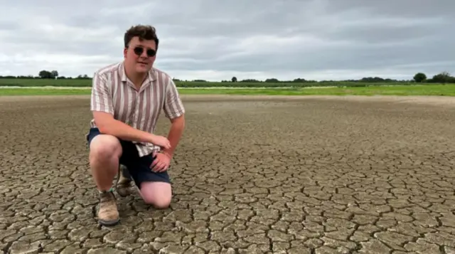 Mike Wilkins wearing a striped shirt kneeling on dry land