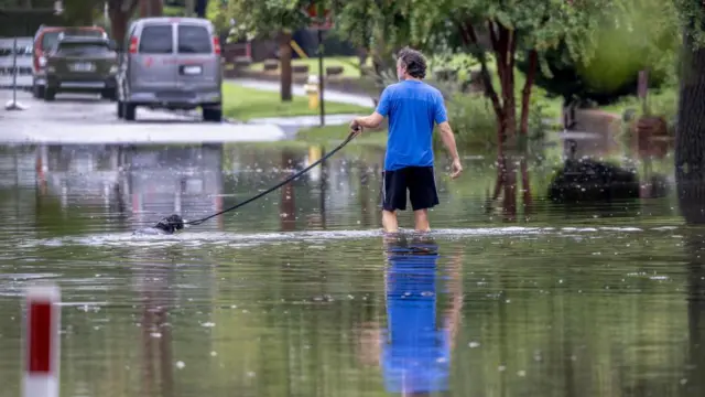 A man and a dog walk through a flood street in South Carolina