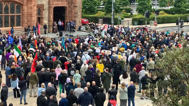People wave flags at an Anti racism rally at the guildhall in Derry