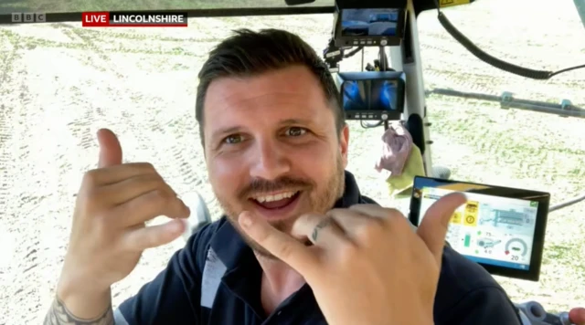 Farmer Jack in Lincolnshire makes devil's horns hand gestures to the camera in the back of his cab