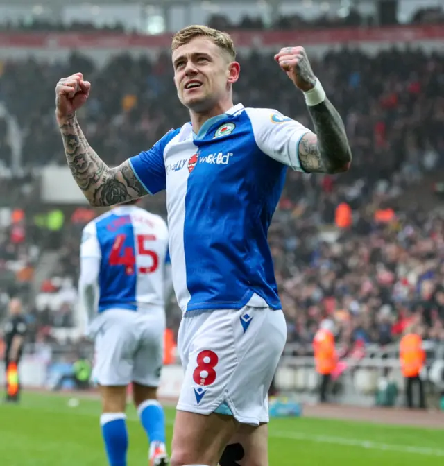 Sammie Szmodics, wearing Blackburn's blue and white kit, raises his fists to head height and clenches them after scoring a goal at Sunderland.