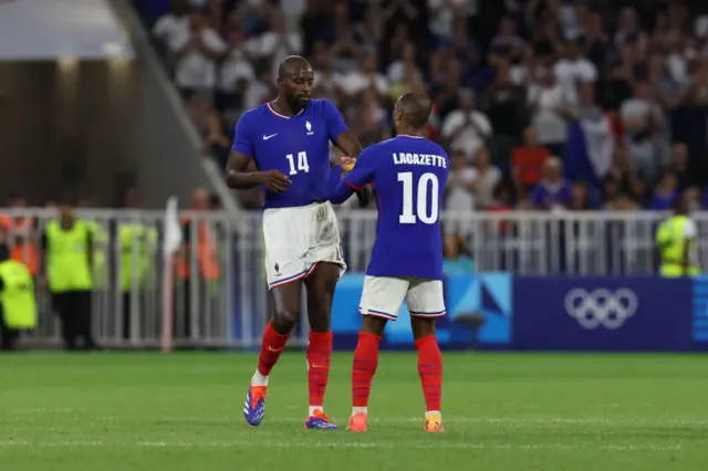 Alexandre Lacazette #10 of Team France gives his captain's armband to teammate Jean-Philippe Mateta