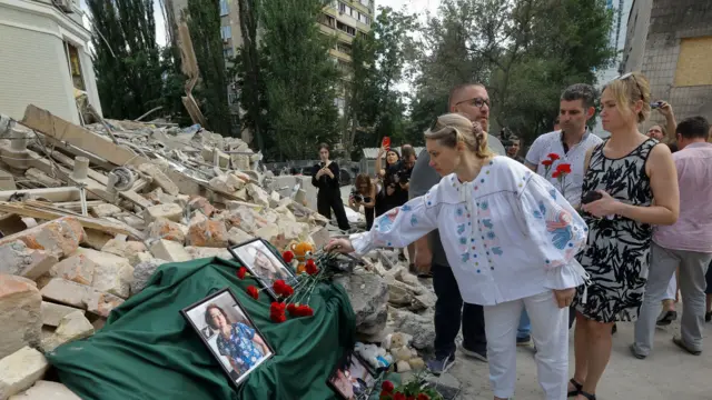 Ukrainians lay flowers for those who died after a missile strike on a children's hospital in Kyiv in July