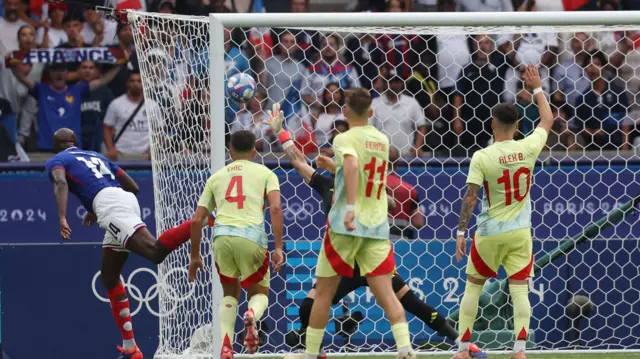 Arnau Tenas makes a save from Jean-Philippe Mateta as Spain play France in the men's football final at the Paris 2024 Olympics