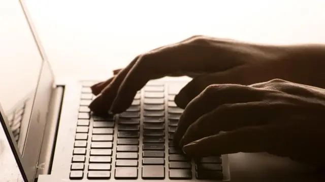 The picture of a laptop with hands typing over it