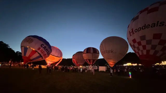 Hot air balloons on the ground in Bristol. They are being lit with fire.