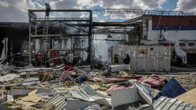 Firefighters work at a site of a supermarket heavily damaged by a Russian military strike