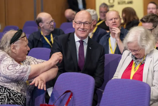 First Minister John Swinney speaks with delegates during the SNP annual national conference at the Edinburgh International Conference Centre