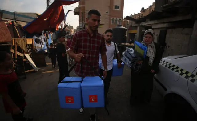 A man carries doses of the vaccine