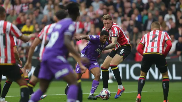 Edo Kayembe with the ball holds off a tackle