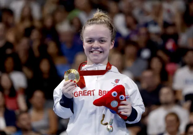 Maisie Summers-Newton on the podium holding her Paralympic gold medal