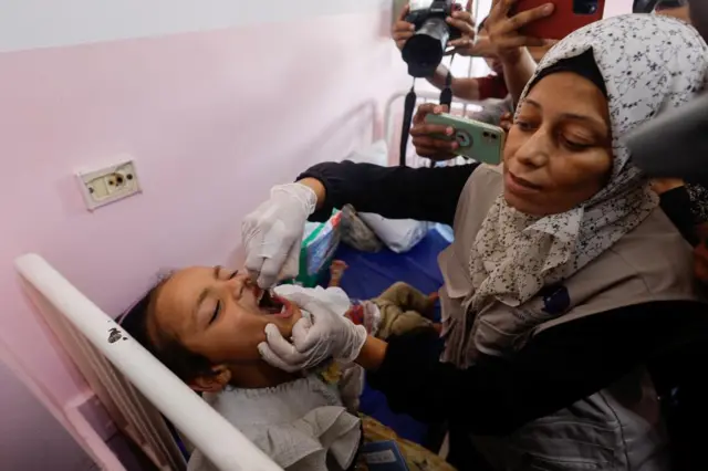 Health worker gives child drops into their mouth on hospital bed