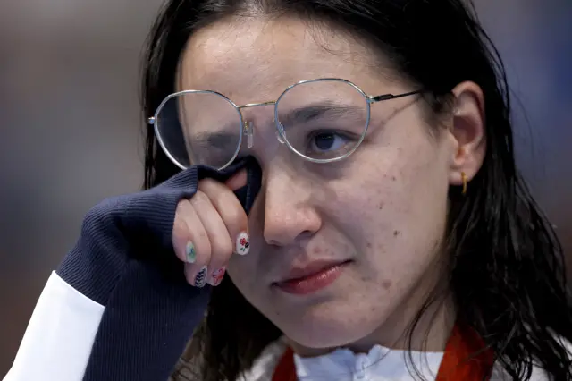 Alice Tai wipes away tears on the podium as she receives her Paralympic gold medal