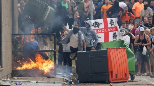 Rioters toss a trash bin during an anti-immigration protest in Rotherham