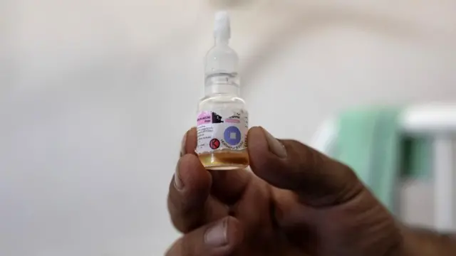 A nurse holds up an oral vaccine