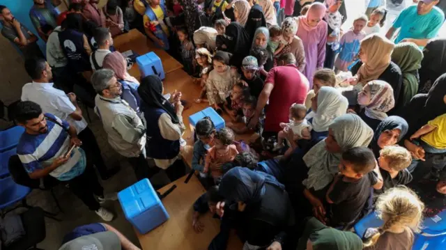 An overhead shot of children waiting for their vaccines accompanied by adults