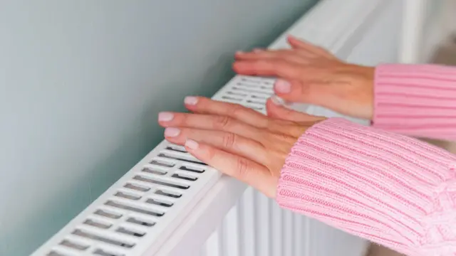 A stock image of a person checking the heat from their heater