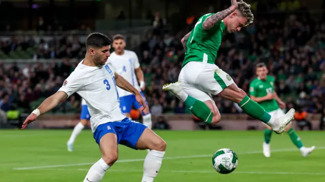 Greece defender Konstantinos Koulierakis closes in as Sammie Szmodics hurdles the ball