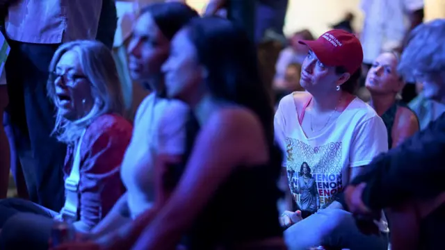 A woman wears a red cap that says “Made you look Kamala 2024” as she watches the presidential debate at a watch party in Mesa, Arizona