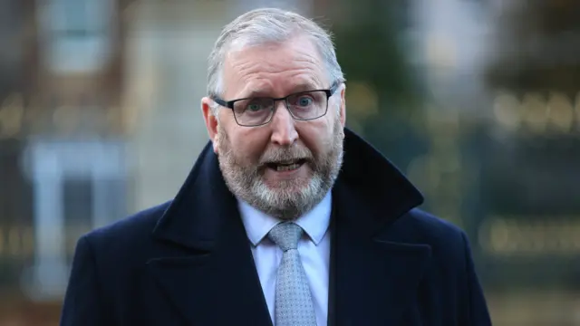 Doug Beattie wearing a navy coat, blue shirt and grey tie, he is wearing glasses