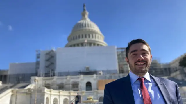 Man, smiling at camera, standing in front of US Capitol building