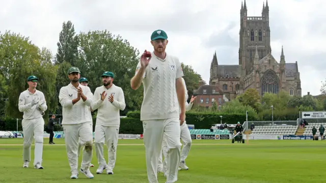 Tom Taylor shows off his Kookaburra ball as he leaves the field at Worcester following his career-best 6-28 against Warwickshire