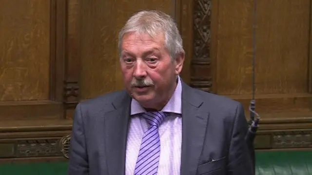 Sammy Wilson wearing a purple shirt and tie with a grey blazer