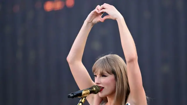 Taylor Swift making a love heart with her hands while performing