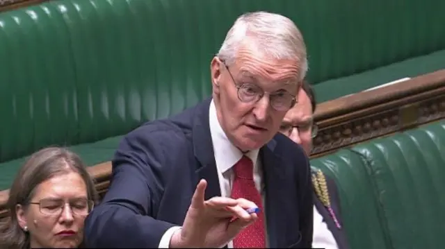 Hilary Benn wearing a navy blazer and red tie