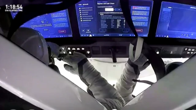 Astronauts on spacecraft with view of screens showing information about flight