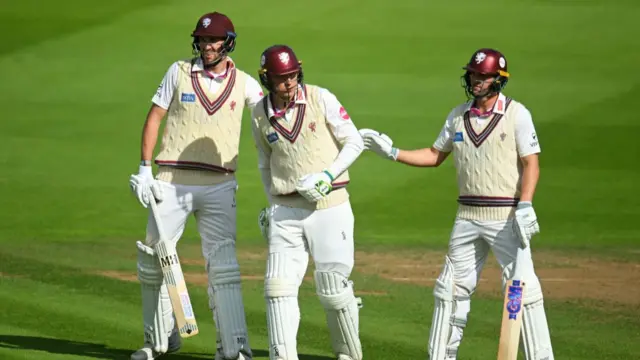 Tom Banton of Somerset interacts with team mate Craig Overton and runner Tom Lammonby