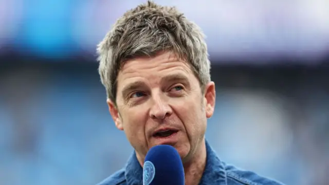 Noel Gallagher being interviewed at a Manchester City game