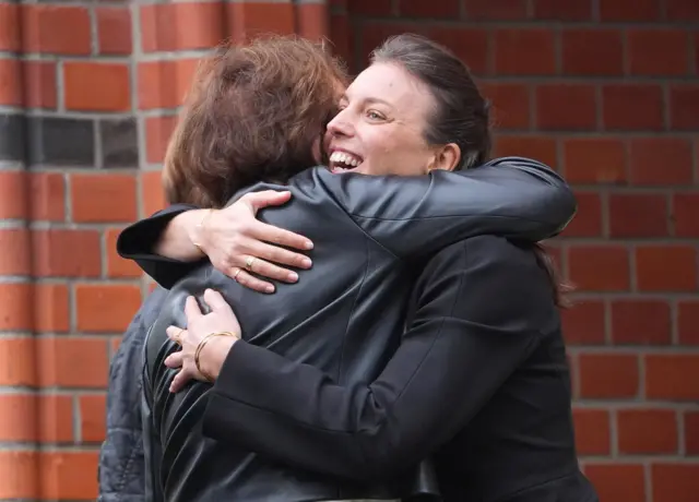 Daughter Lina hugs a mourner as they arrive