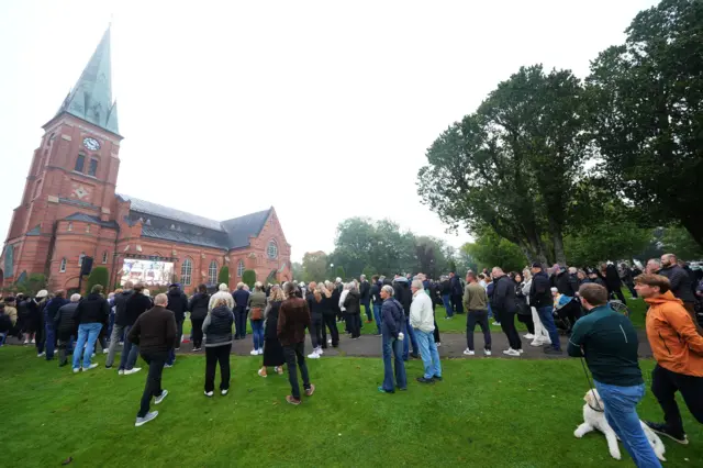 People watching on a big screen outside the funeral service of Sven-Goran Eriksson at Fryksande Church in Torsby, Sweden.