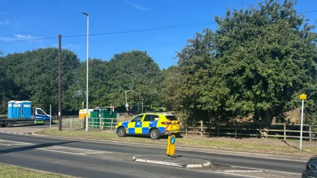 A police car parked on the grass verge at the side of a road in Luton