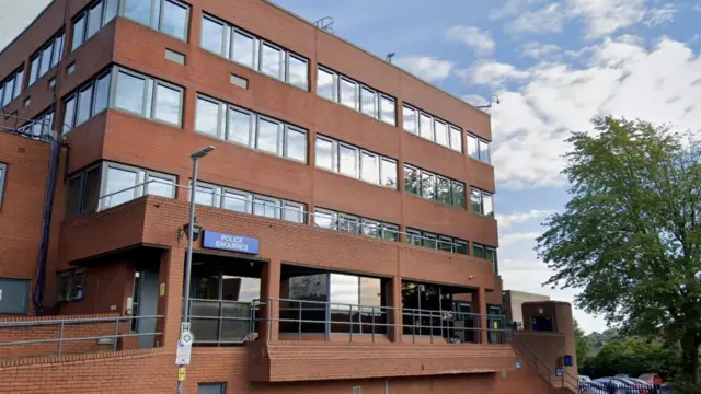 The outside of Luton police station. It is a multi-story office building with red bricks and windows.