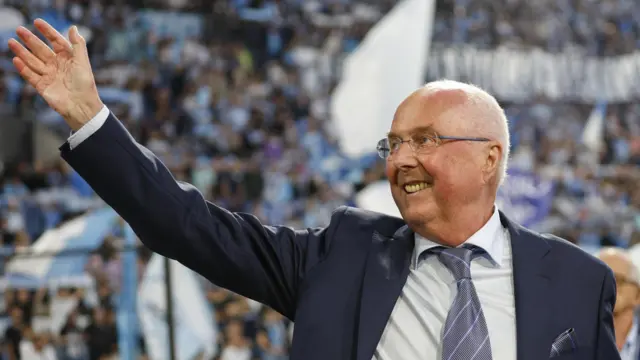 Sven-Goran Eriksson with arm up and smile on face at football stadium