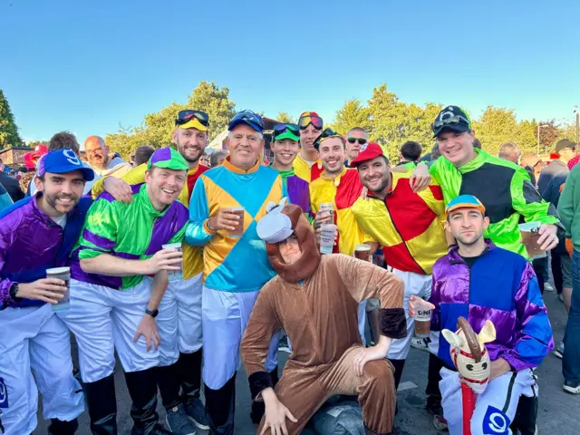 A group of men dressed as jockeys and one horse