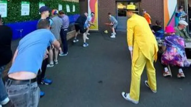 Fans play cricket behind the stands