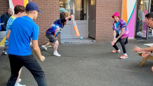 Fans playing cricket outside the ground