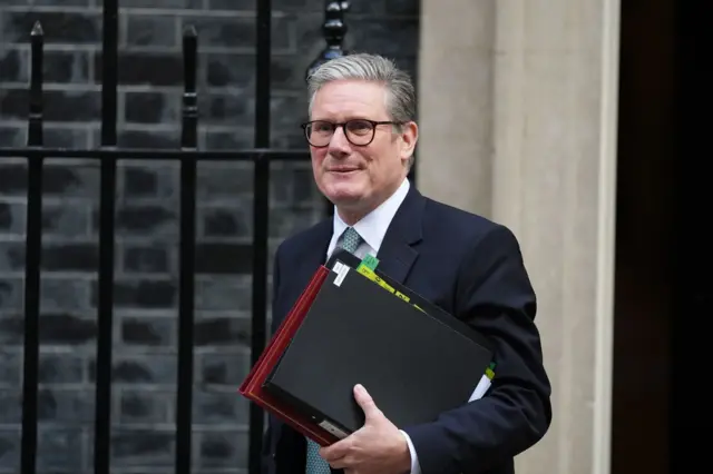 Keir Starmer walking in Downing Street holding files and folders