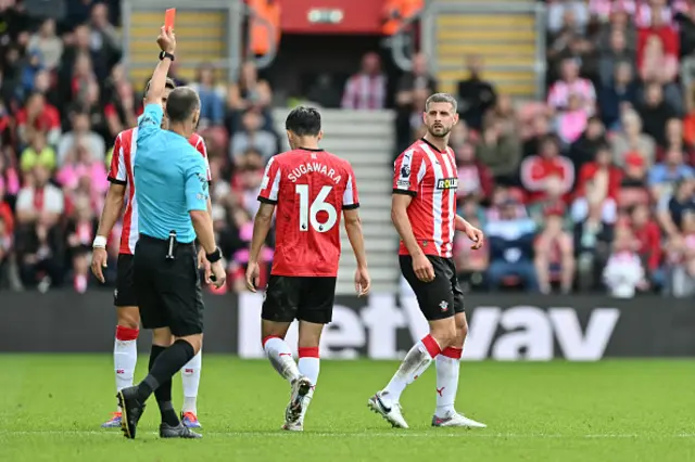 Jack Stephens (R) reacts as he receives a red card