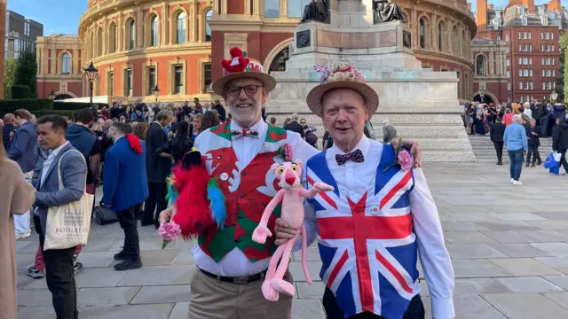 A man with a Union Jack waistcoat and another with a Welsh waistcoat, standing in front of the Royal Albert Hall